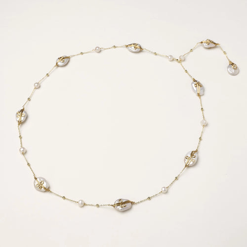 Delicate gold-plated necklace featuring translucent leaf-shaped baroque pearls and round freshwater pearls on neutral background.