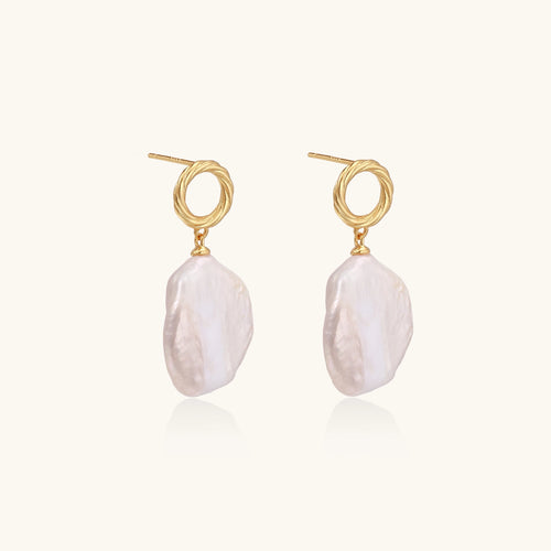 Gold-plated twisted stud earrings with large blush baroque pearls hanging elegantly on white background.