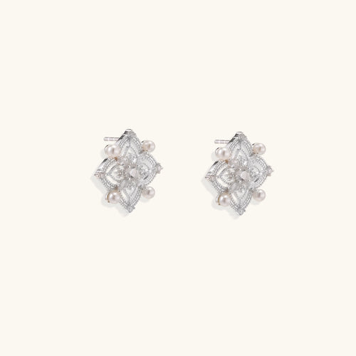 Detailed view of sterling silver stud earrings with geometric filigree design and small freshwater pearls on white background.