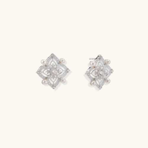 Detailed view of sterling silver stud earrings with geometric filigree design and small freshwater pearls on white background.