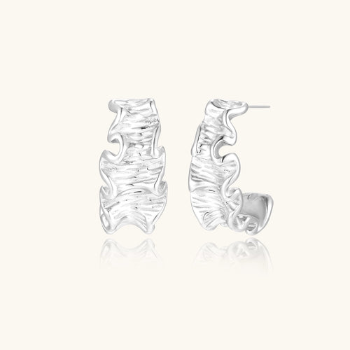 Textured gold-plated hoop earrings with flowing ripple design displayed on clean white background.