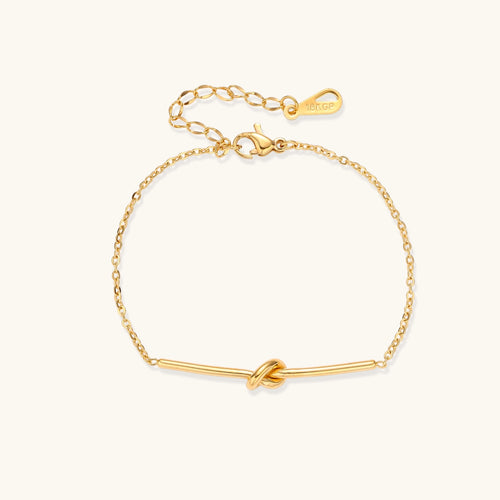 Delicate gold-plated chain bracelet with twisted knot bar detail and adjustable extender chain on white background.
