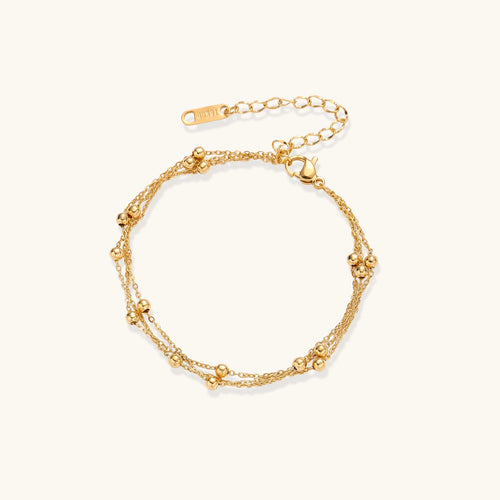 Delicate 18K gold plated bracelet with spherical beads on layered chains and adjustable extender on white background