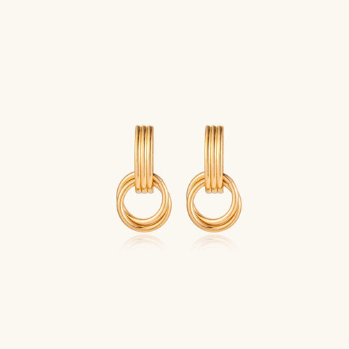 Geometric gold earrings with ribbed linear top section and circular drop elements on white background.