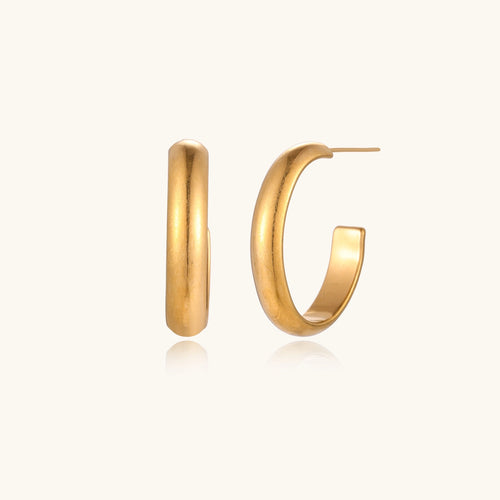 Four pairs of gold-plated stainless steel earrings including hoops and studs displayed on cream background